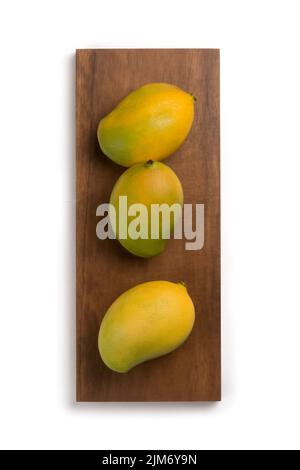 Reife Mangos, tropische Früchte auf Holzplatte, isoliert auf weißem Hintergrund, direkt von oben aufgenommen Stockfoto