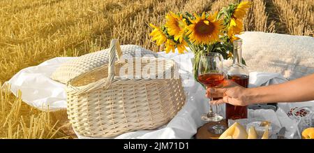 Junge Frau mit Picknick mit Früchten und Wein im Weizenfeld Stockfoto