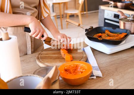 Junge Frau schneidet Kürbis in der Küche, Nahaufnahme Stockfoto