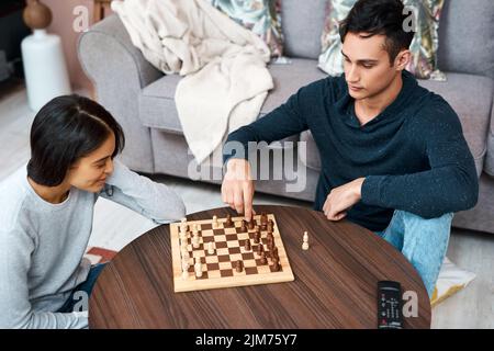 Wie wird Ihr Lockdown ausspielen? Ein junges Paar, das zu Hause ein Schachspiel spielt. Stockfoto