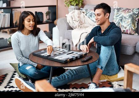 Die gesunde Art des Spielens. Ein junges Paar spielt zu Hause ein Backgammon-Spiel. Stockfoto