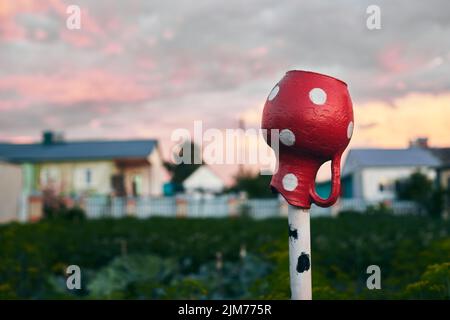 Im Sommer ein roter Keramikkrug auf einer Stange auf dem Land. Ländliche Idylle. Vorderansicht. Stockfoto