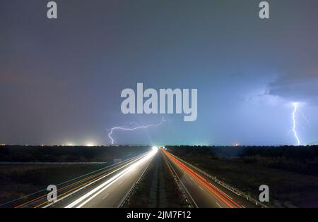 Ein Blick in die Nacht mit dem Blitz am Horizont und Lichtwegen in einem Feld in Extremadura, Spanien Stockfoto