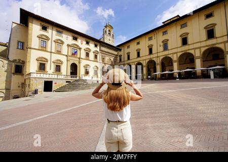 Reisen in der Toskana. Rückansicht eines Mädchen mit Hut auf dem Piazza Grande Platz in der historischen Stadt Arezzo, Toskana, Italien. Stockfoto