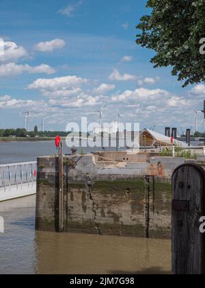 Antwerpen, Belgien, 02. Juli 2022, Alte Kaimauer am rechten Ufer mit Blick auf das linke Ufer von Antwerpen mit blauem Himmel und Wolken Stockfoto