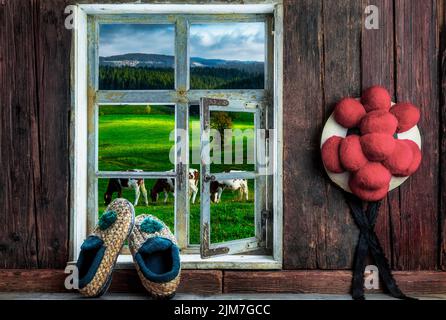 Rustikale Bauernstube mit Bollenhut und Strohfinken und Blick in die Landschaft Stockfoto