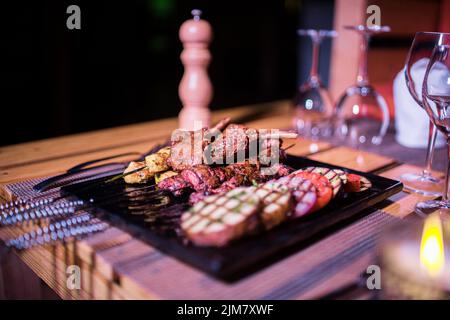 Ein Teller mit Huhn und Rindfleisch BBQ mit einem Glas frischen Mojito Drink auf der Seite Stockfoto