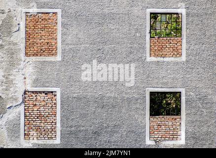 Die Wand des alten Hauses mit gemauerten Fenstern. Textur, Hintergrund, illustratives Foto Stockfoto