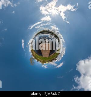 Winziger Planet in blau bedecktem Himmel mit schönen Wolken mit Umwandlung von kugelförmigem Panorama 360 Grad. Sphärische, abstrakte Luftaufnahme. Curvatur Stockfoto