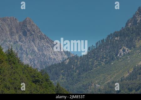 Blick auf die Hänge verschiedener Berggipfel rund um das Valbona-Tal im Norden Albaniens, mit Bäumen, Tannen und felsigen Berglandschaften. Stockfoto