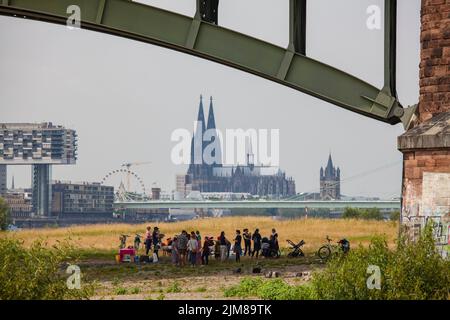 Gruppe von Menschen unter der Südbrücke, Blick auf den Rheinauer Hafen mit den Kranichhäusern und auf den Dom, Köln, Deutschland. People is be Stockfoto