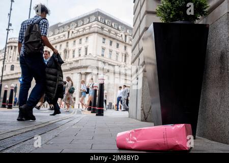 Am Tag, an dem die Bank of England eine Zinserhöhung von 1,25% auf 1,75% ankündigte, die höchste Erhöhung seit 27 Jahren, liegt am 4.. August 2022 in der City of London, England, eine Einkaufstasche am Boden in der Nähe eines Außenbereichs der Bank of England. Dieser Anstieg wird weithin als ein Abgleiten in Richtung Inflation mit einer Schrumpfung der britischen Wirtschaft gesehen - der Beginn seines Rückgangs in die Rezession im dritten Finanzquartal 2022. Stockfoto