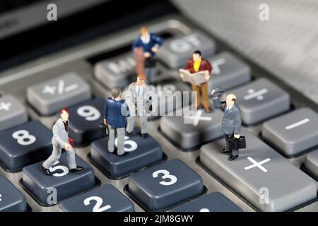 Miniaturmänner schütteln sich die Hände auf einem Rechner Stockfoto