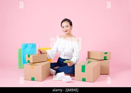 Glückliche junge asiatische Unternehmer arrangieren Boxen für die Lieferung von Produkten an Kunden. Stockfoto