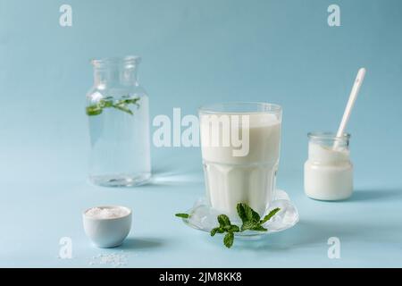 Ayran oder Doogh ist ein beliebtes erfrischendes Getränk aus dem Nahen Osten, das aus Joghurt, Wasser und Salz hergestellt wird. Blauer Hintergrund Stockfoto