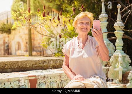 Reife Frau Reisende sitzen auf der Treppe und mit dem Handy Stockfoto