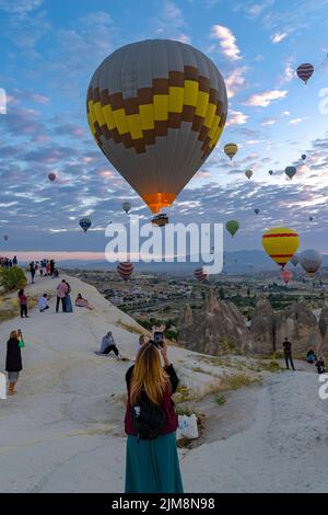 GOREME/TÜRKEI - 30. Juni 2022: Heißluftballon fliegt in der Nähe der Touristen . Stockfoto