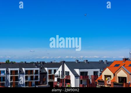 Flugzeug fliegen im Himmel über einem modernen Mehrfamilienhaus in einem städtischen Wohnviertel, modernes Wohnen im urbanen Raum Stockfoto