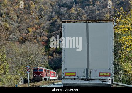 Die Strecke der Schmalspurbahn und des Zuges mit roter Lokomotive und Wagen kommt vom Septemvri Bahnhof nach Dobrinishte über den Rhodope Mountan Stockfoto