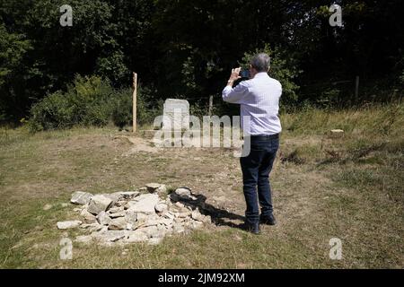 Ein Mann fotografiert den Stein, der den Ort für die traditionelle Quelle der Themse markiert, die als Thames Head bekannt ist, eine Gruppe von saisonalen Quellen in der Nähe des Dorfes Coates in den Cotswolds, Gloucestershire. Ausgetrocknete Teile Englands stehen unter sehr trockenen Bedingungen und vor einer weiteren vorhergesagten Hitzewelle vor einem Schlauchleitungsverbot. Bilddatum: Freitag, 5. August 2022. Stockfoto