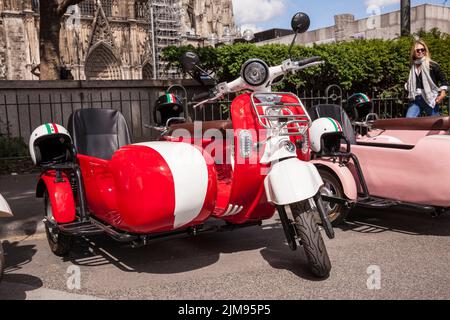 E-Vespina Roller mit Seitenwagen können für Stadtrundfahrten in der Nähe des Kölner Doms gemietet werden. E-Vespina Roller mit Seitenwagen stehen z Stockfoto