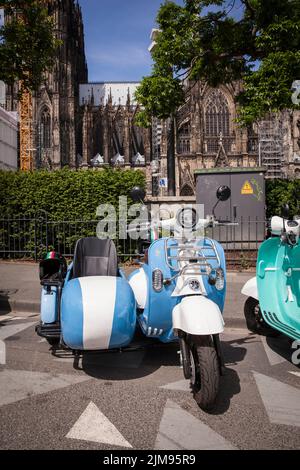 E-Vespina Roller mit Seitenwagen können für Stadtrundfahrten in der Nähe des Kölner Doms gemietet werden. E-Vespina Roller mit Seitenwagen stehen z Stockfoto