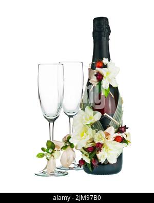 Champagner-Flasche und Glas mit Hochzeitsdekoration von Blumenarrangements. Stockfoto