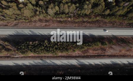 Autobahnstraße zwischen tiefem Wald in Ural, Russland. Schöne herbstliche Naturlandschaft bei tagsüber. Luftaufnahme von einer Drohne Stockfoto