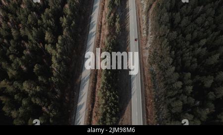 Autobahnstraße zwischen tiefem Wald in Ural, Russland. Schöne herbstliche Naturlandschaft bei tagsüber. Luftaufnahme von einer Drohne Stockfoto