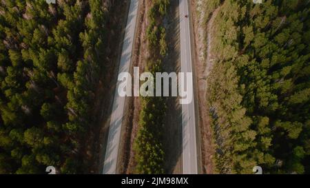 Autobahnstraße zwischen tiefem Wald in Ural, Russland. Schöne herbstliche Naturlandschaft bei tagsüber. Luftaufnahme von einer Drohne Stockfoto
