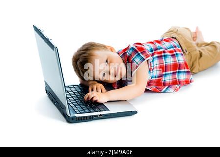 Junge in einem karierten Hemd mit einem Laptop auf weißem Hintergrund. Stockfoto