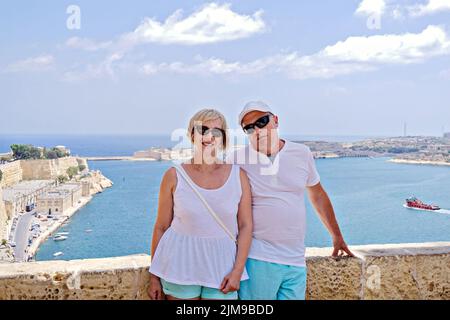 Ein Paar von Babyboomern mittleren Alters, die am sonnigen Sommertag in Valletta auf Malta auf dem blauen Meer posieren, um Fotos zu machen. Ausleger nach Ende c fahren Stockfoto