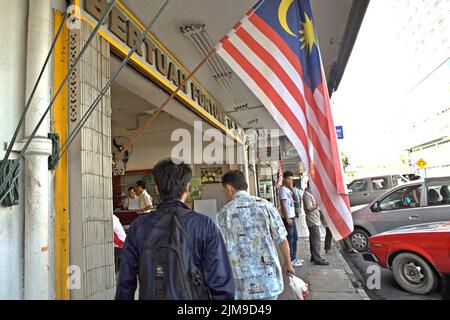 Menschen, die auf einem Gehweg am Straßenrand in einem Geschäftsviertel in Kota Kinabalu, Sabah, Malaysia, spazieren und stehen. Stockfoto