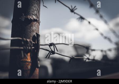 Stacheldrahtzaun gegen dramatischen, dunklen Himmel. Stockfoto