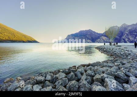 Nago–Torbole, Italien - 26. Februar 2022: Blick auf das Nordufer des Gardasees, mit Einheimischen und Besuchern, an einem klaren Wintertag, in Nago–Torbole, Tren Stockfoto