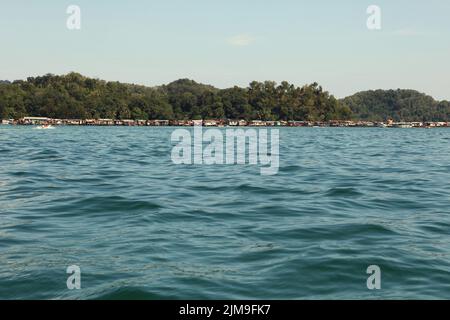 Stelzenhäuser einer Bajau Laut (Sea Gypsy) Gemeinschaft werden von einem Boot gesehen, das auf dem Meer im Tunku Abdul Rahman Park in Sabah, Malaysia, segelt. Stockfoto