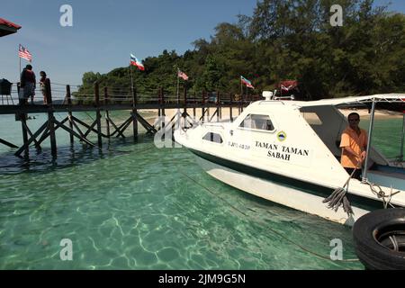 Ein Touristenboot auf dem Küstenwasser von Pulau Sapi (Sapi Insel), einem Teil des Tunku Abdul Rahman Parks in Sabah, Malaysia. Stockfoto