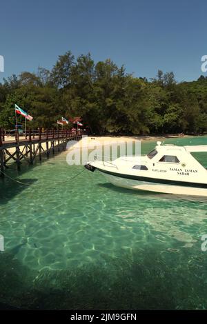 Ein Touristenboot auf dem Küstenwasser von Pulau Sapi (Sapi Insel), einem Teil des Tunku Abdul Rahman Parks in Sabah, Malaysia. Stockfoto