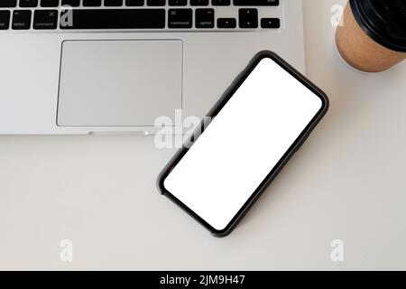 Nahaufnahme von Smartphone und Computer auf weißer Tischansicht. Modell mit weißem Bildschirm. Stockfoto