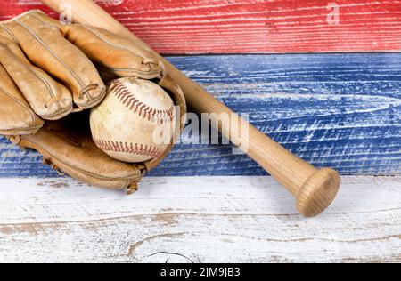 Alte, abgenutzte Baseballausrüstung auf verblassten Brettern, die in amerikanischen Nationalfarben gestrichen sind Stockfoto