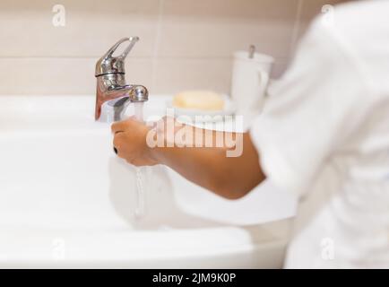 Junge wäscht seine Hand mit fließendem Leitungswasser im Badezimmer. Stockfoto
