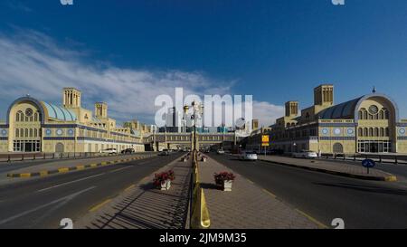 Atemberaubende Architektur des Sharjah Al Jubail Fish Market aus der Mitte zweier Straßen an einem sonnigen Tag in den Vereinigten Arabischen Emiraten; Panorama von außen. Stockfoto