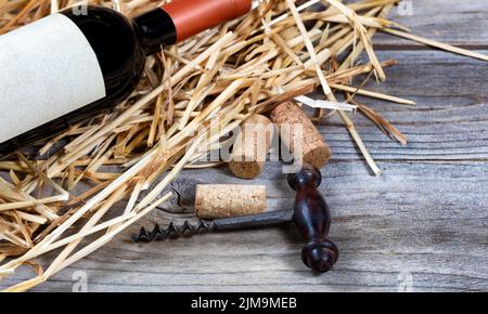 Jahrgangswein Korkenzieher mit Flasche Wein auf Stroh im Hintergrund Stockfoto