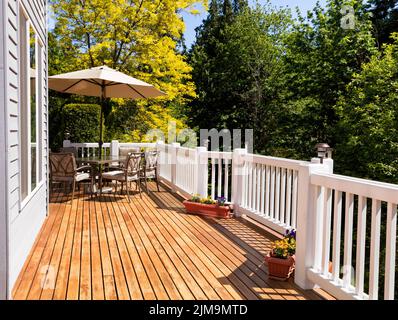 Startseite Outdoor Zederndeck mit blühenden Bäumen und blauem Himmel im Hintergrund Stockfoto