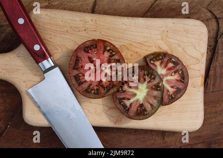 Geschnittene schwarze Tomaten auf einem Ahornschneidebron Stockfoto