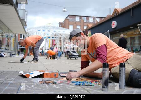 Wilhelmshaven, Deutschland. 05. August 2022. Der mexikanische Straßenkünstler José Méndez malt im Rahmen des Internationalen StreetArt Festivals in der Innenstadt von Wilhelmshaven. Das Festival feiert sein 10.-jähriges Bestehen und 60 Künstler, darunter aus Mexiko, Japan, Algerien, Pakistan, Italien und die Niederlande werden an der Straßenmalerei teilnehmen. Auf einer Fläche von jeweils einem Quadratmeter können Kinder und Jugendliche am Samstag und Sonntag ihrer Kreativität freien Lauf lassen. Quelle: Markus Hibbeler/dpa/Alamy Live News Stockfoto