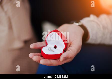 Heiratsantrag. Mann halten Verlobungsring am roten Kasten in der hand Stockfoto