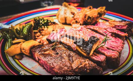 Nahaufnahme einer Mahlzeit der Bistecca alla Fiorentina auf einem bunten Teller auf dem Tisch Stockfoto