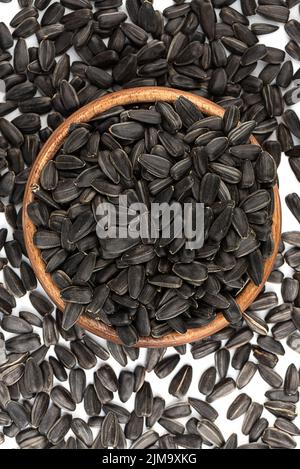 Draufsicht auf ungeschälte Sonnenblumenkerne in und um die Schüssel. Nahaufnahme. Stockfoto