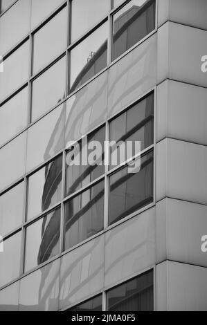 Eine vertikale Graustufenaufnahme von Gebäuden, die in der Fensterscheibe von Media Harbor reflektiert werden. Düsseldorf, Deutschland. Stockfoto